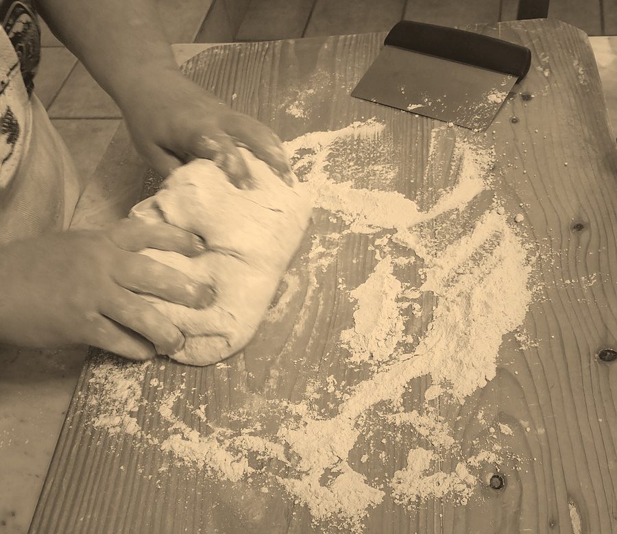 Mani che impastano il pane su un tavolo infarinato (foto illustrativa)
